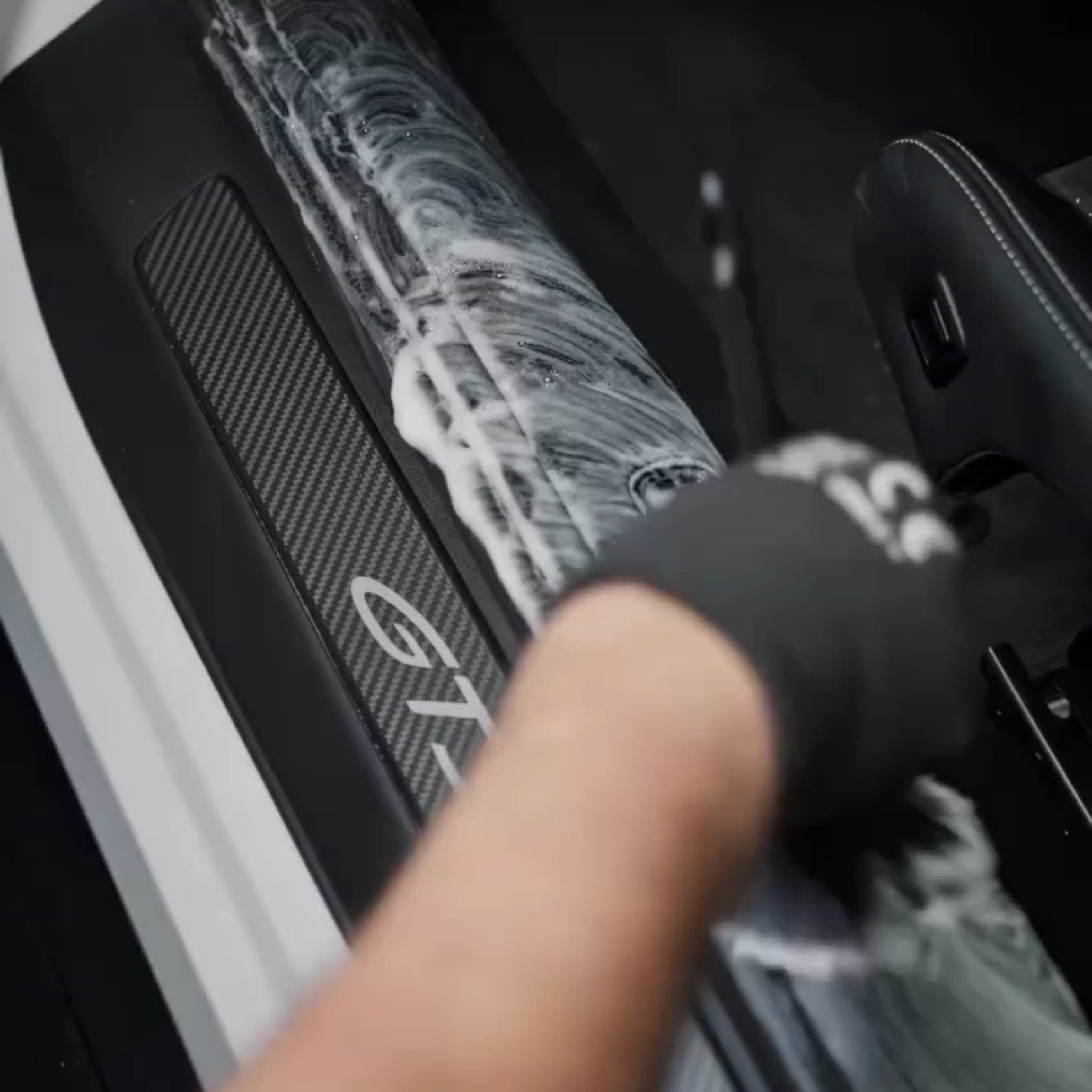 Detailer brushing a car door sill clean during an interior detail
