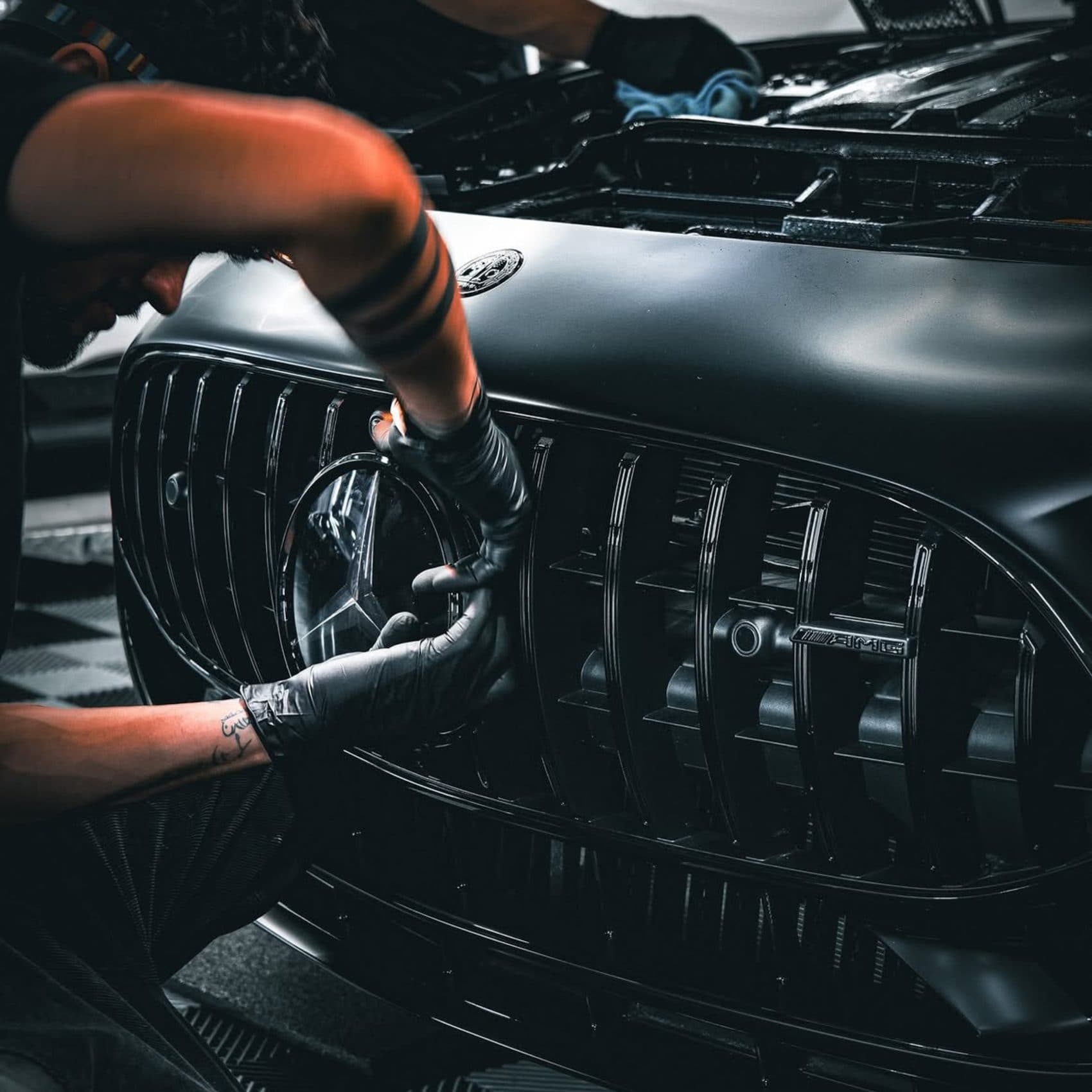 Detailer cleaning the grille of a black Mercedes by hand