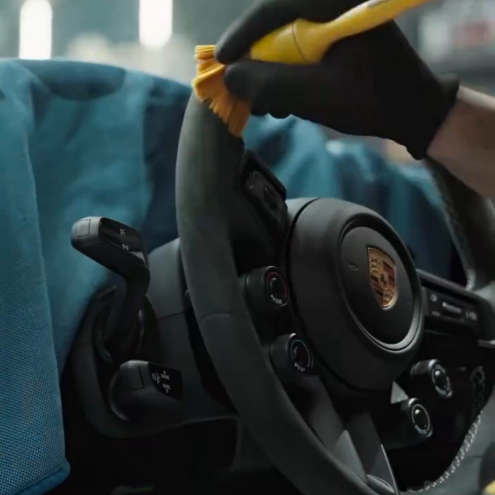 Gloved detailer cleaning and conditioning a car steering wheel